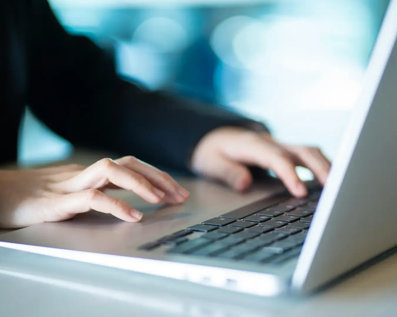 Hände tippen auf einer Laptop-Tastatur